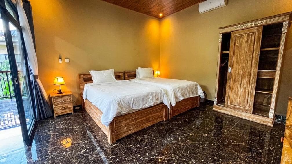 Room with two single beds, a carved wardrobe and a door to the terrace