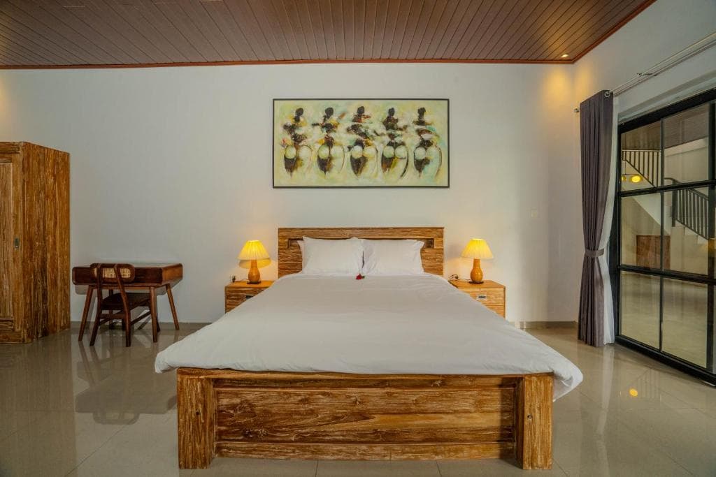 Room with a large double bed, a desk and glass doors