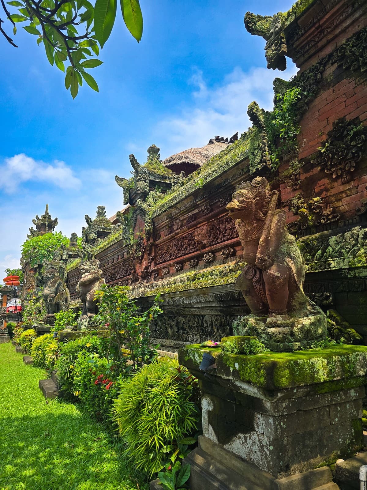 Carved outer wall of the palace with a stone lion and a garden