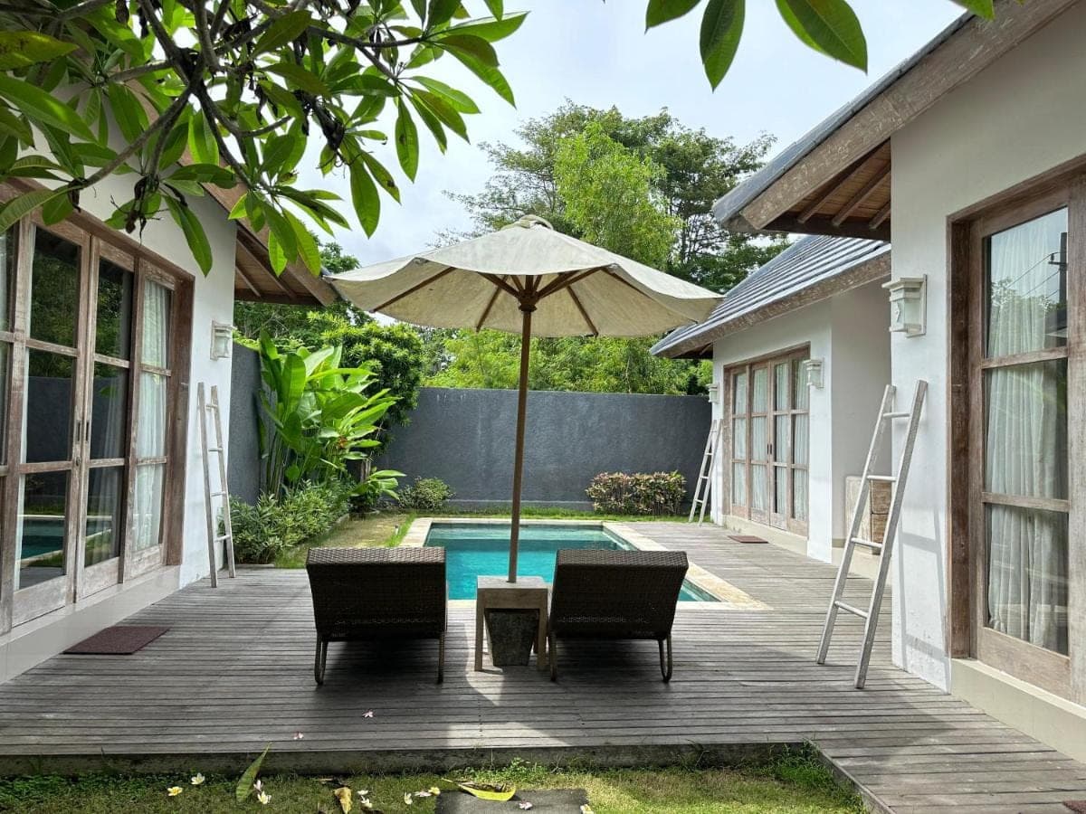 a patio with chairs and an umbrella next to a pool at Bingin Garden Uluwatu in Uluwatu