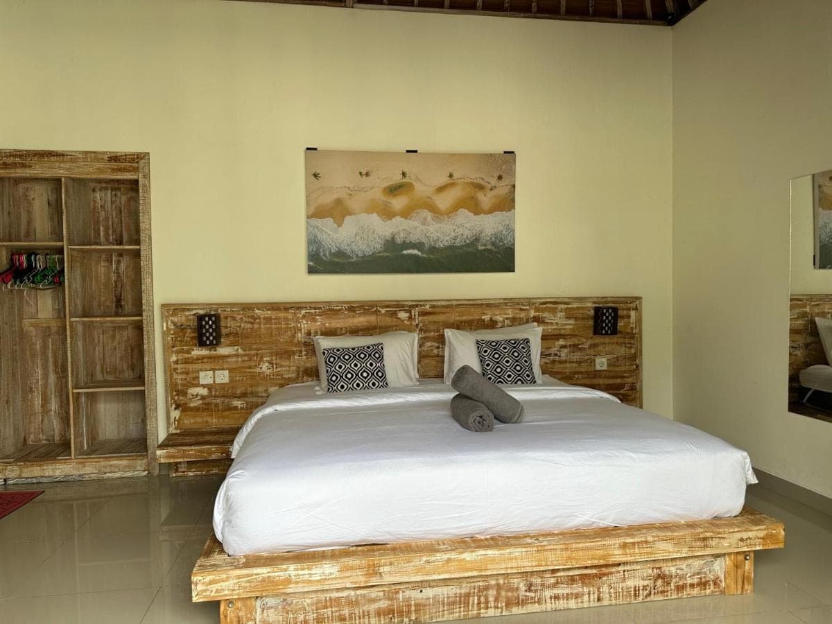 a bedroom with a large bed with a wooden headboard at Bingin Garden Uluwatu in Uluwatu