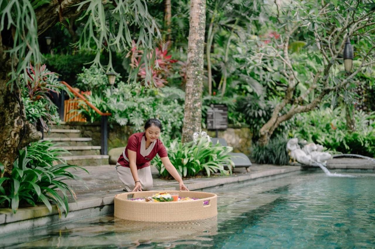 a woman kneeling next to a box in the water at Arkamara Dijiwa Ubud in Ubud