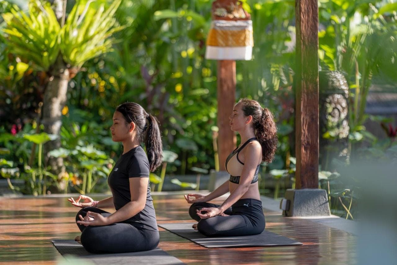 two women are sitting in a yoga pose at Arkamara Dijiwa Ubud in Ubud