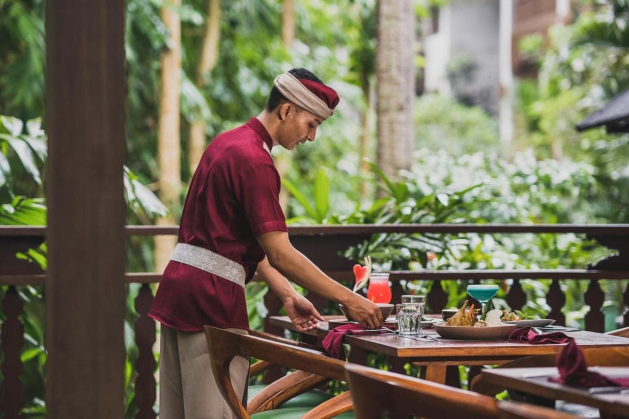 a man standing at a table in front of a table at Arkamara Dijiwa Ubud in Ubud