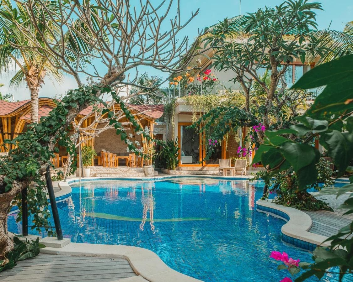 a pool at a resort with trees and a building at MJ Villa Sanur in Sanur