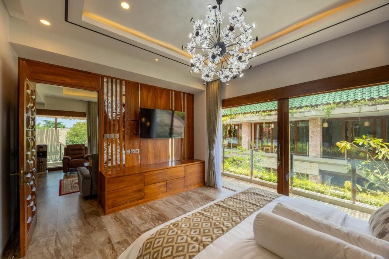 a bedroom with a large bed and a chandelier at MJ Villa Sanur in Sanur