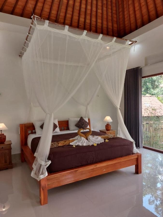 a bedroom with a bed with a canopy at Pondok Kukuh Sidemen in Sidemen