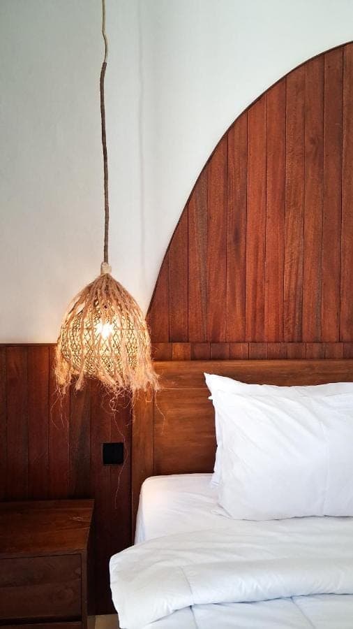 a bed with a wooden head board and a chandelier at Heritage Stay in Uluwatu