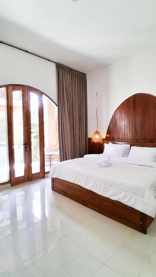 a bedroom with a large bed with a wooden headboard at Heritage Stay in Uluwatu