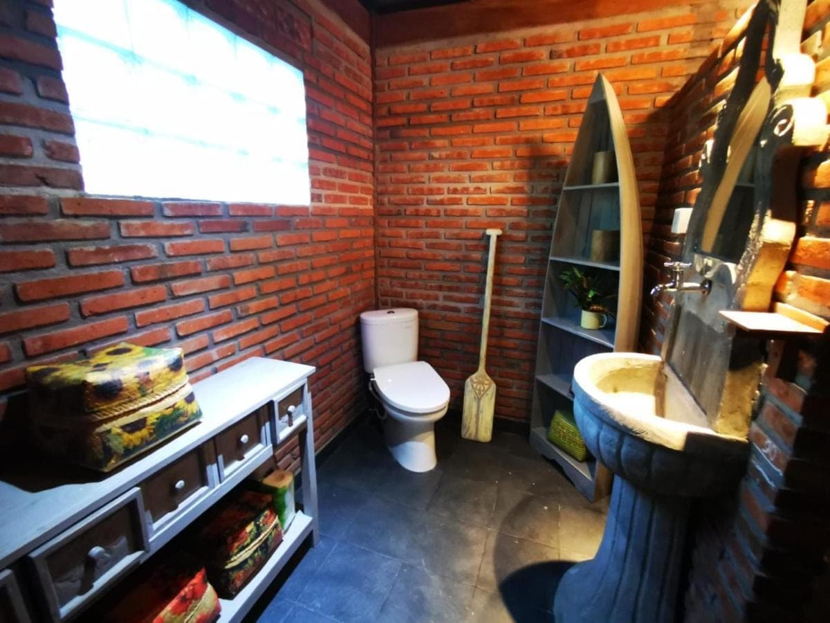 a brick bathroom with a toilet and a sink at Villa Kong in Amed