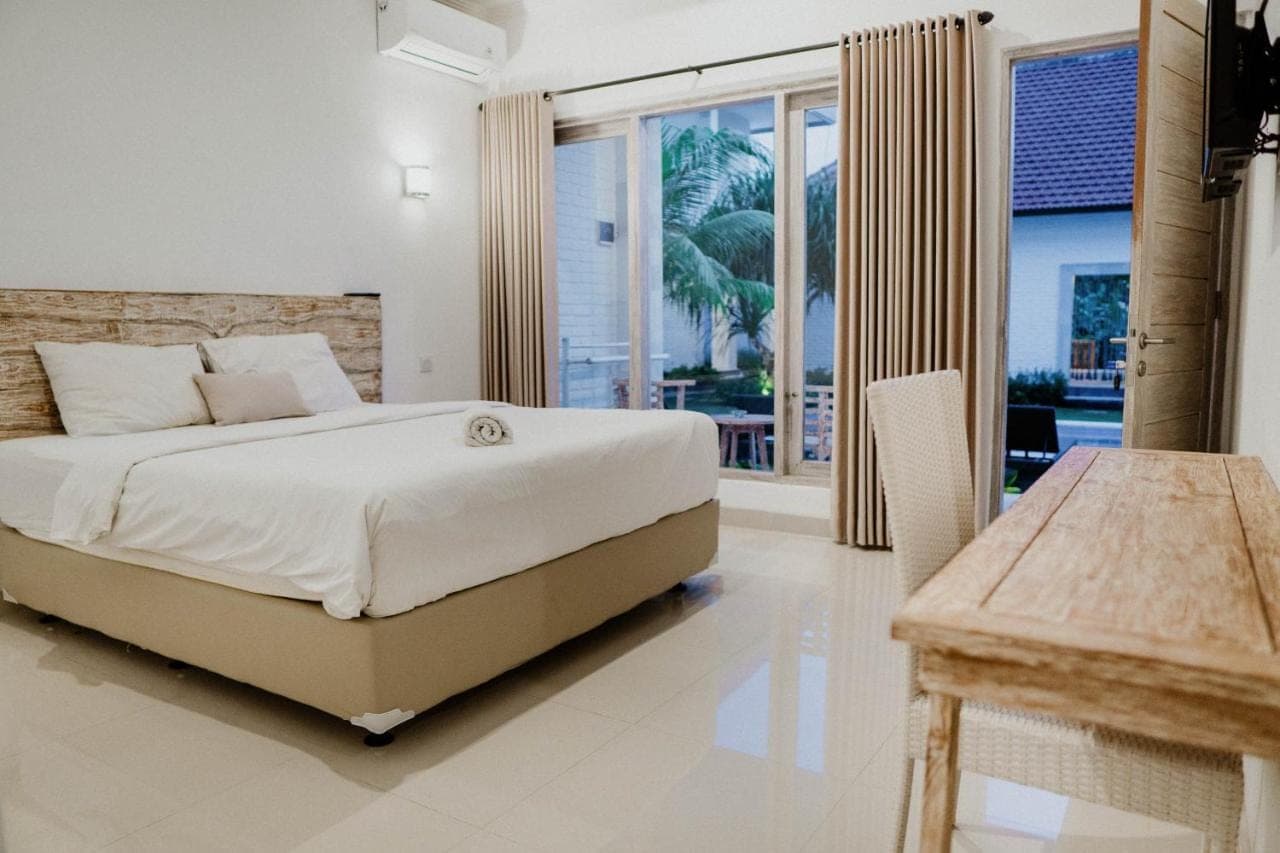 a bedroom with a large bed and a balcony at Berawa Dini Guesthouse in Canggu