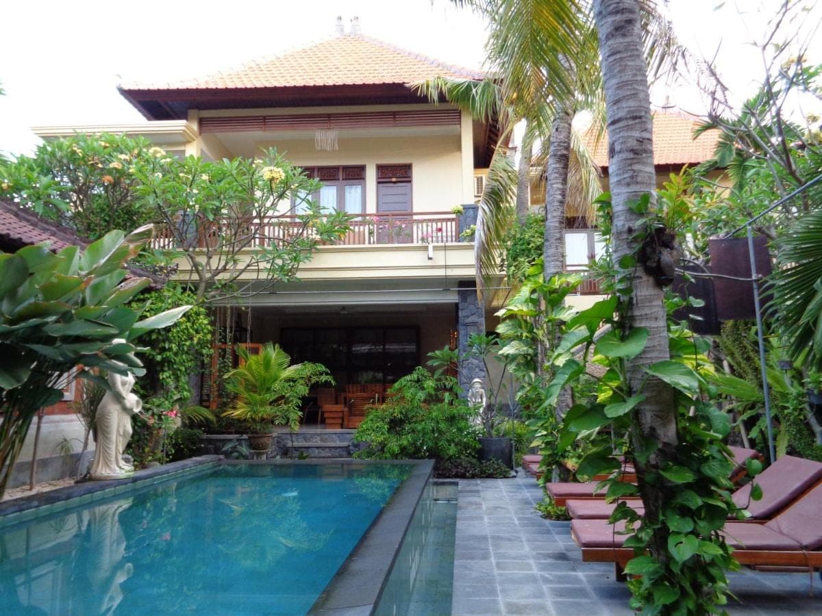a villa with a swimming pool in front of a house at Yulia 1 in Sanur