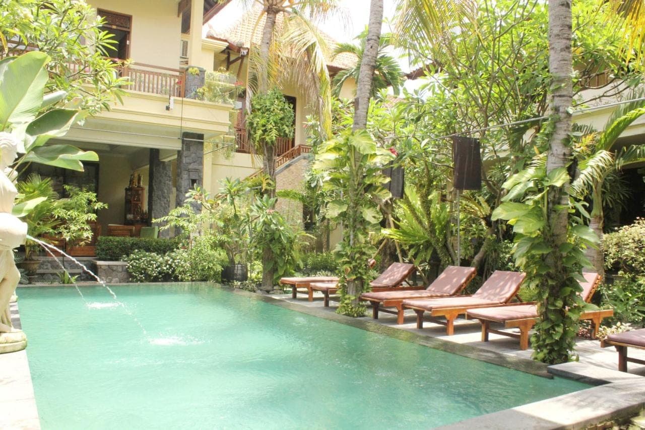 a swimming pool with lounge chairs and a resort at Yulia 1 in Sanur