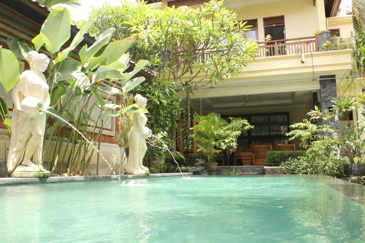 a swimming pool with two statues in front of a building at Yulia 1 in Sanur