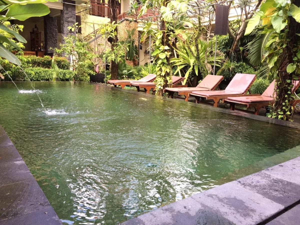 a pool of water with lounge chairs next to it at Yulia 1 in Sanur