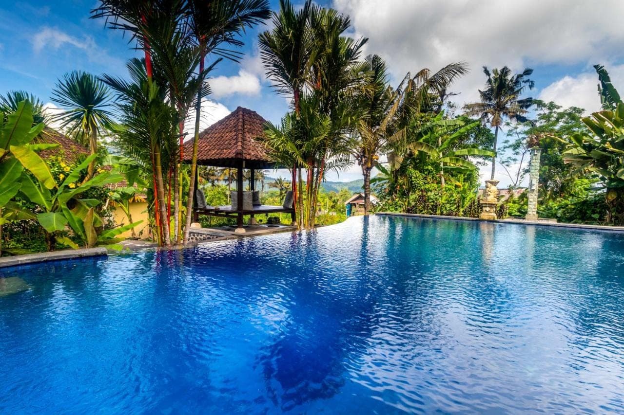 a swimming pool with palm trees and a gazebo at Pelangi Villas Sidemen by AGATA in Sidemen