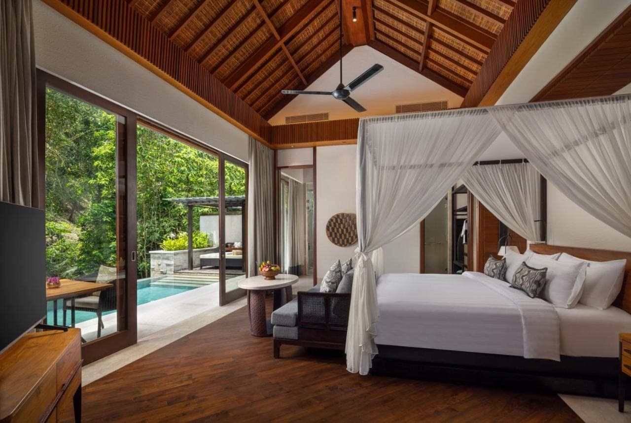 a bedroom with a canopy bed and a pool at Impiana Private Villas Ubud in Ubud