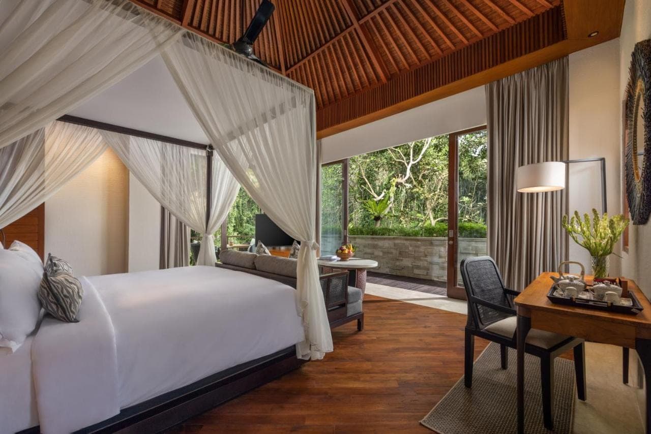 a bedroom with a bed and a desk and a bed and a room with at Impiana Private Villas Ubud in Ubud