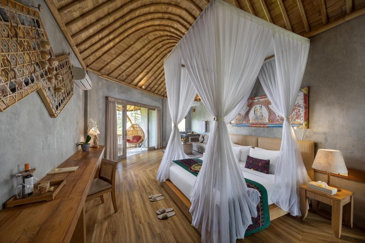 a bedroom with a bed with white mosquito nets at thewakanda Resort A Pramana Experience in Ubud