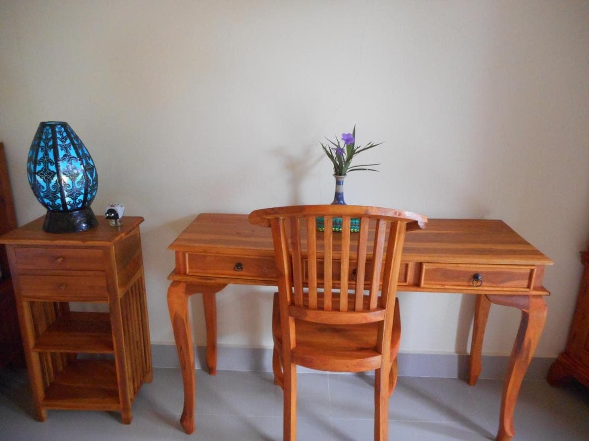 a wooden desk with a chair and a vase with a plant at Eko Homestay in Sidemen