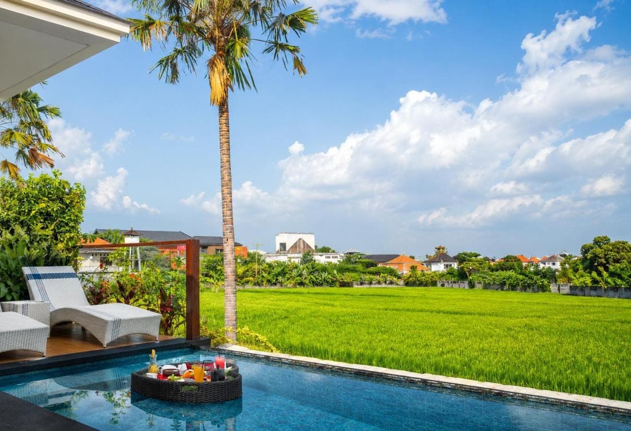 a villa with a pool and a palm tree at The Wina Villa Seminyak, Near Potato Head Beach Club in Seminyak