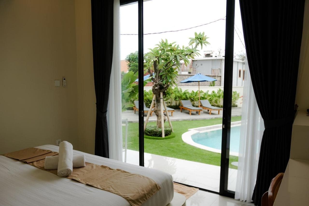a bedroom with a bed and a view of a pool at Kula Uluwatu in Uluwatu