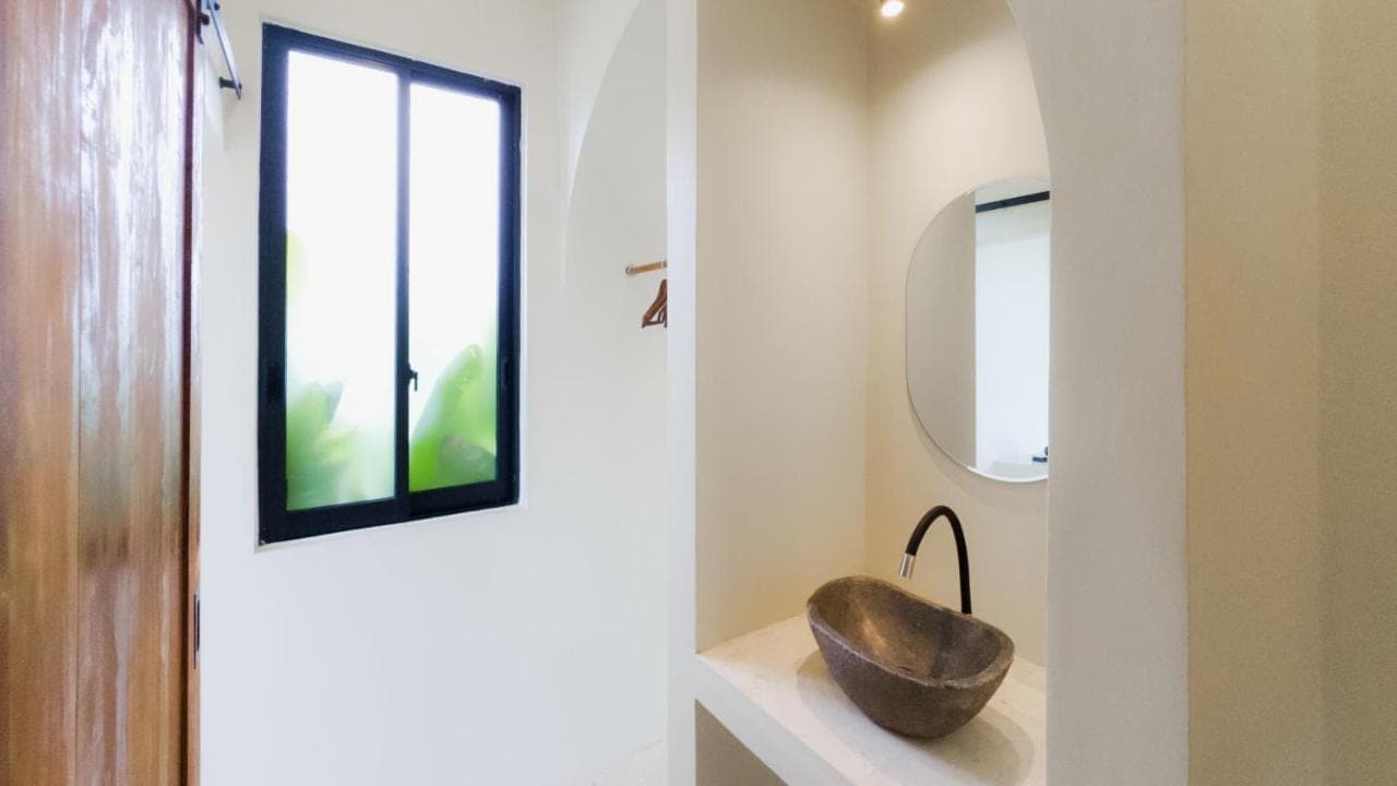 a bathroom with a stone bowl on a shelf next to a mirror at Kula Uluwatu in Uluwatu