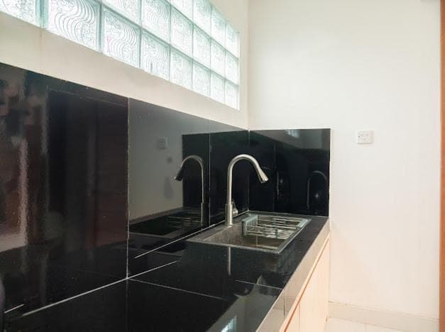 a black bathroom with a sink and two faucets at Aspen bali nusa dua in Nusa Dua