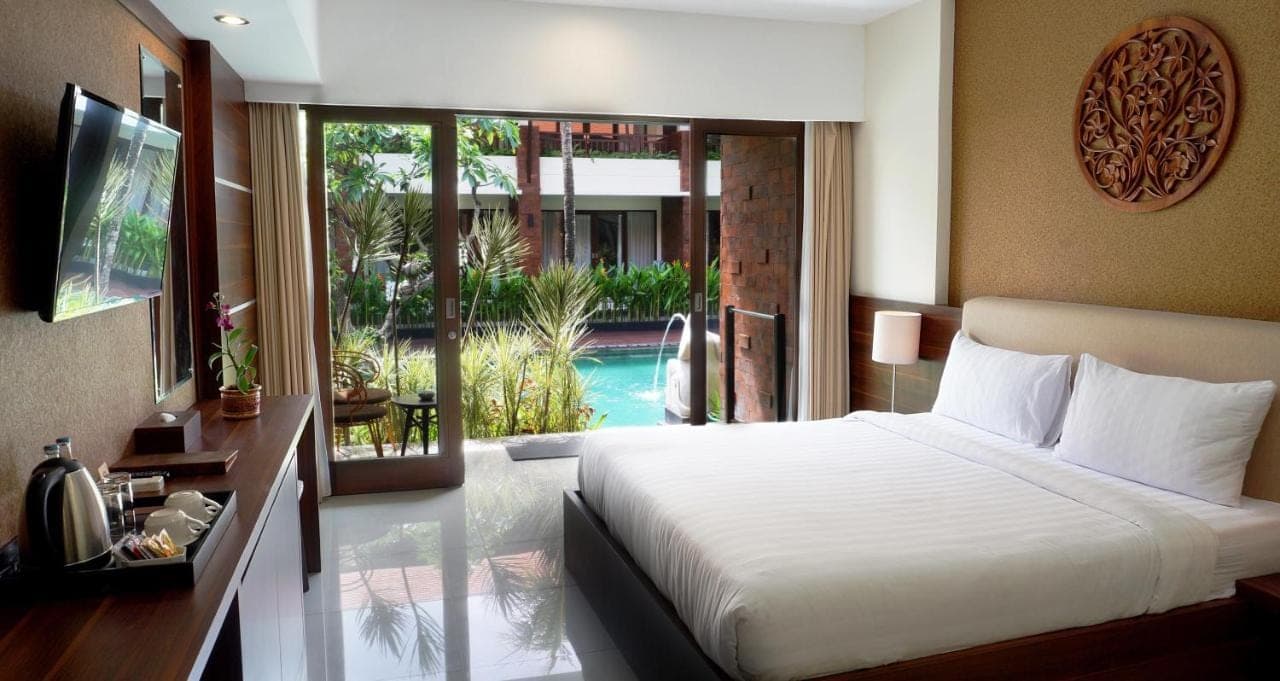 a bedroom with a bed and a view of a pool at Arena Living in Sanur