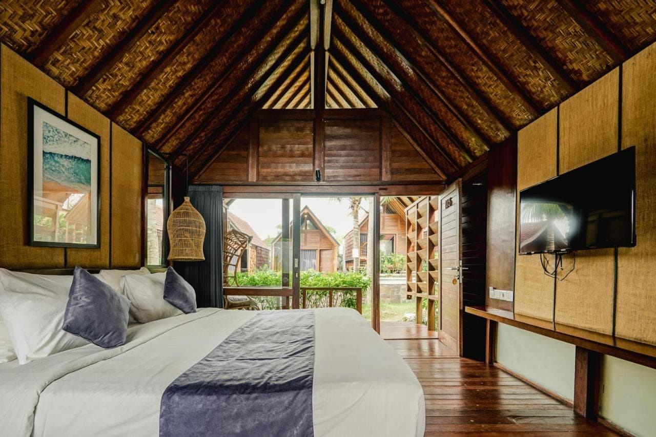 a bedroom with a bed and a large window at Bingin Lodge Uluwatu in Uluwatu
