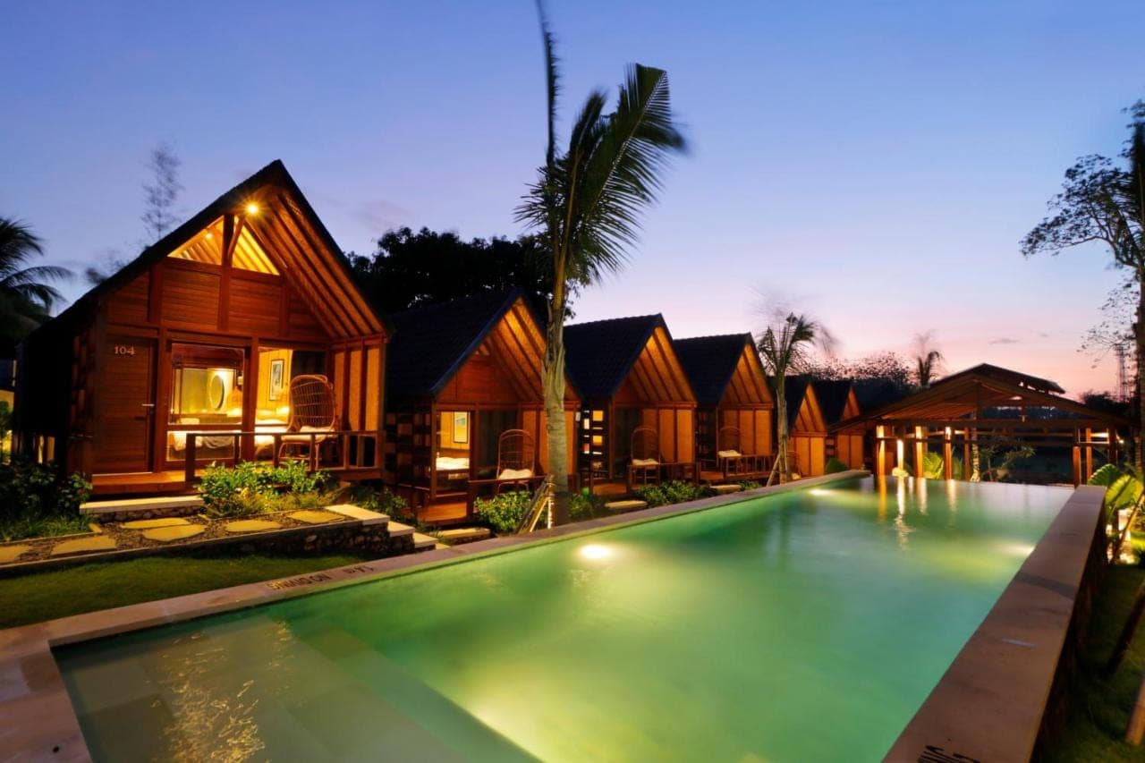 a villa with a swimming pool at night at Bingin Lodge Uluwatu in Uluwatu