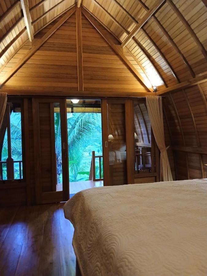 a bedroom with a bed in a room with windows at Lumbung Umaluah Villa in Sidemen