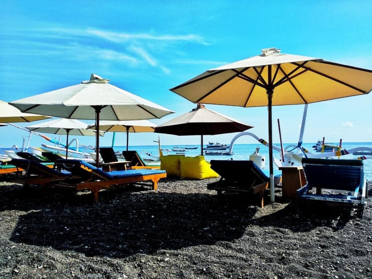 a group of chairs and umbrellas on a beach at COCONUT BEACH BUNGALOWs &amp; WARUNG in Amed