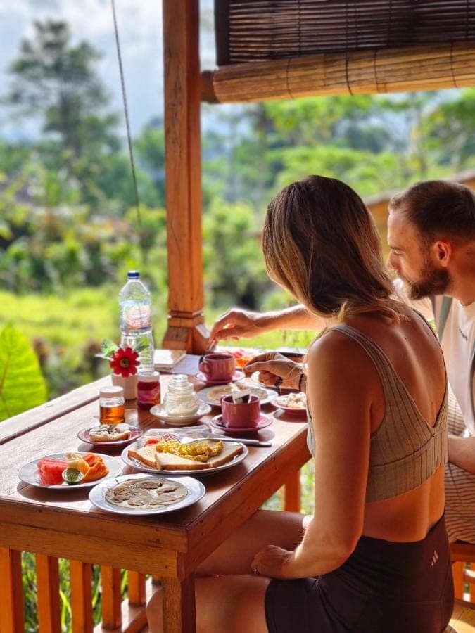 a man and a woman sitting at a table with food at Arta dani villas in Sidemen