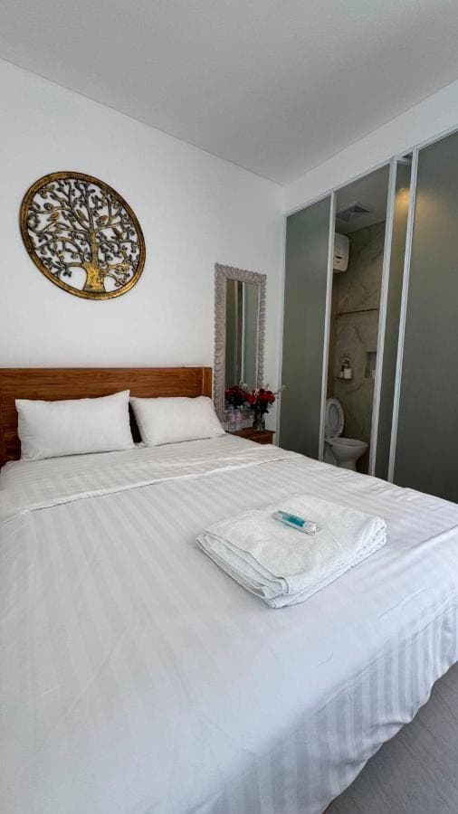 a white bed in a bedroom with a clock on the wall at Roemah Mawar in Sanur
