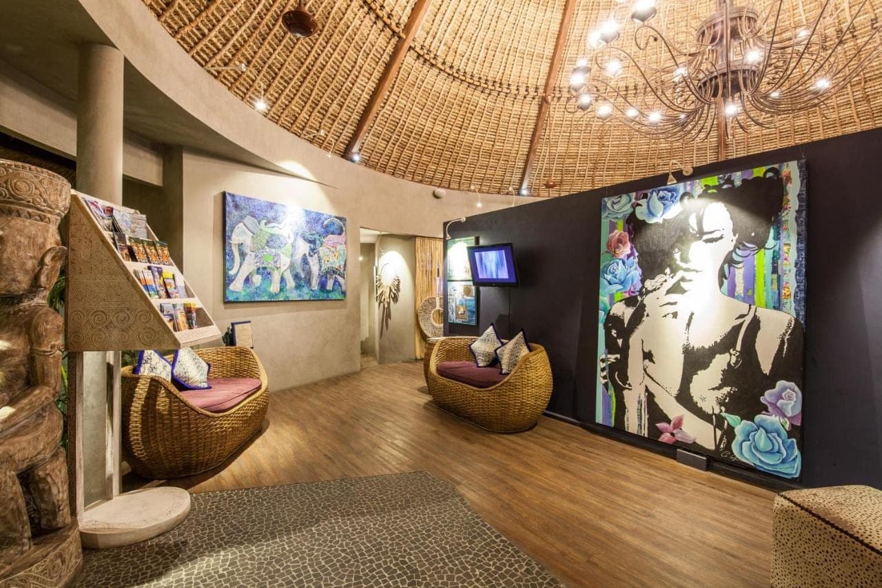 a living room with wicker chairs and a large screen at Blue Karma Seminyak in Seminyak