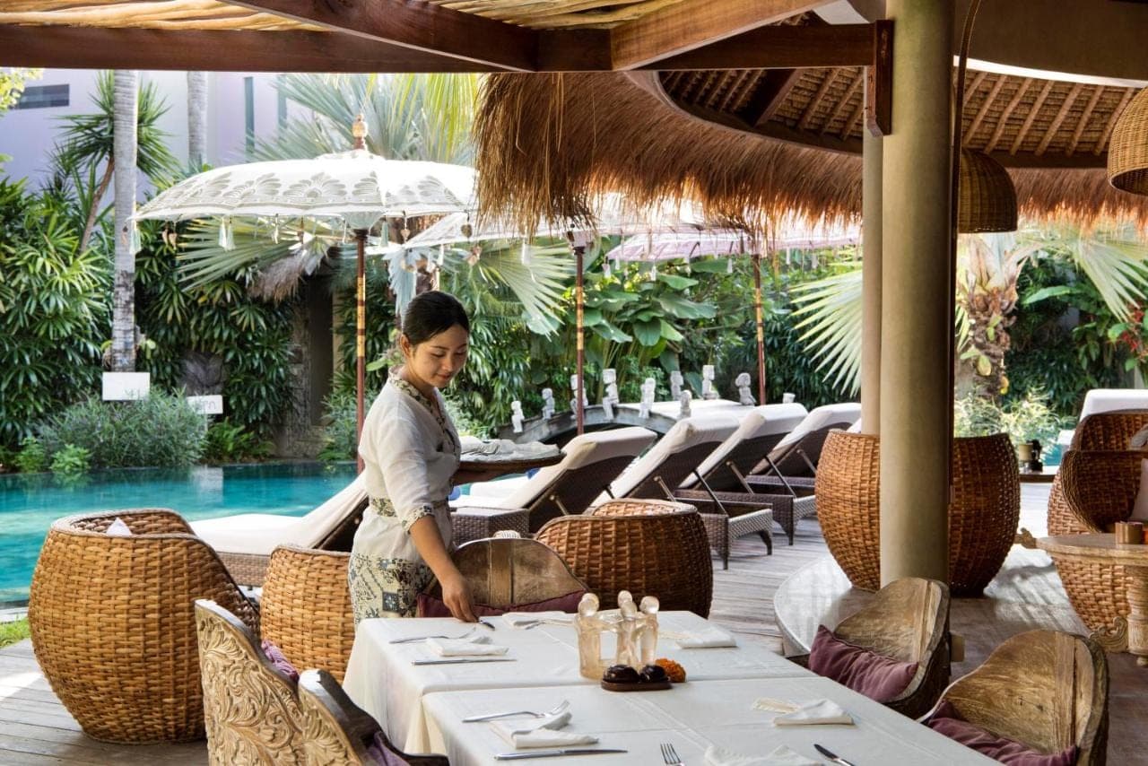a woman standing at a table in a restaurant at Blue Karma Seminyak in Seminyak