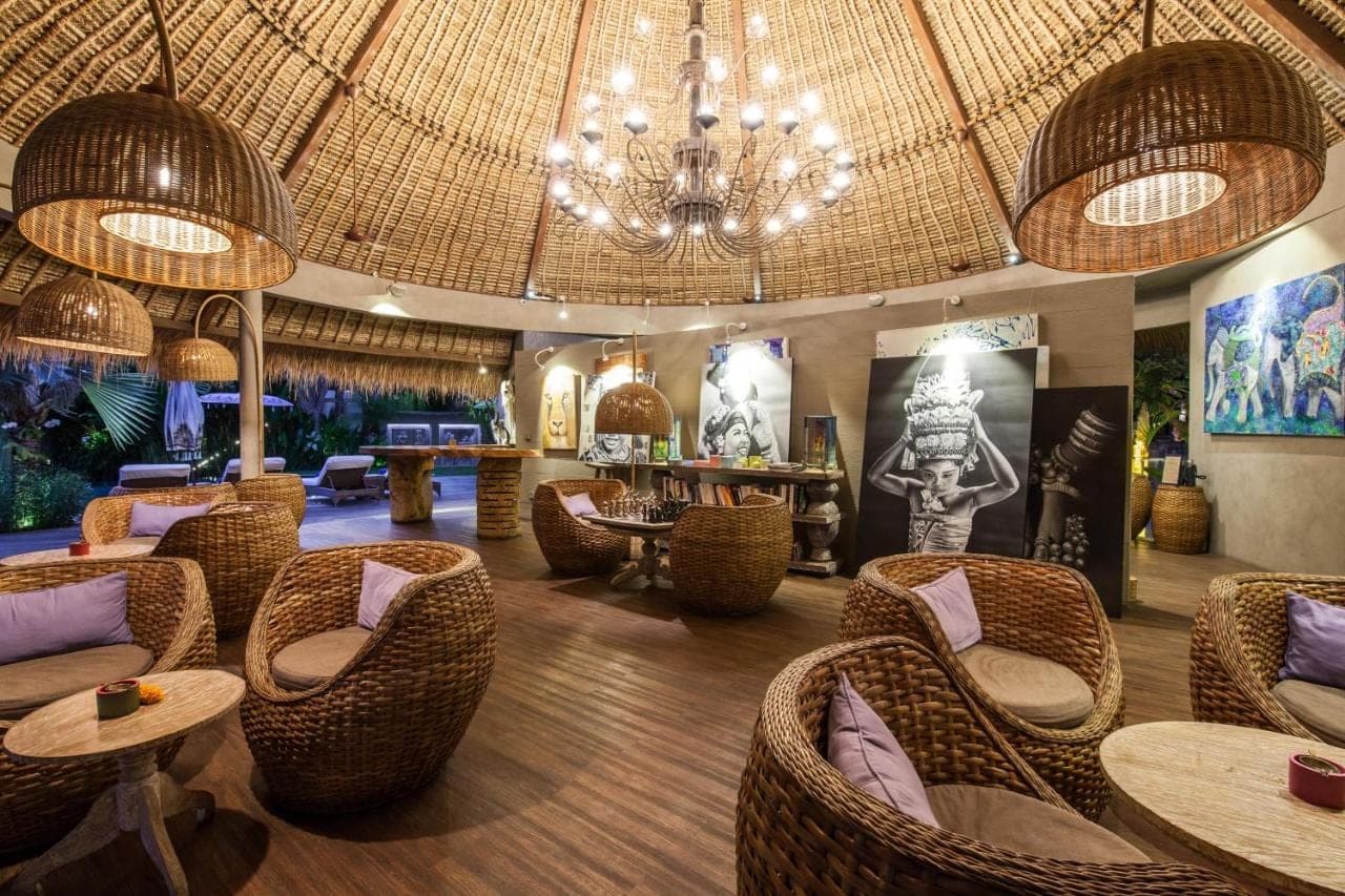 a restaurant with wicker chairs and tables and a chandelier at Blue Karma Seminyak in Seminyak