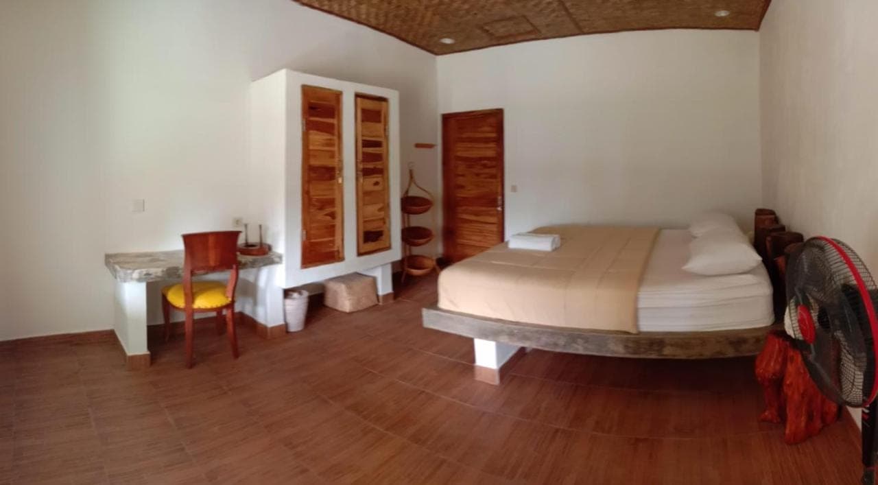 a bedroom with a bed and a table in a room at La Cama Bali in Uluwatu