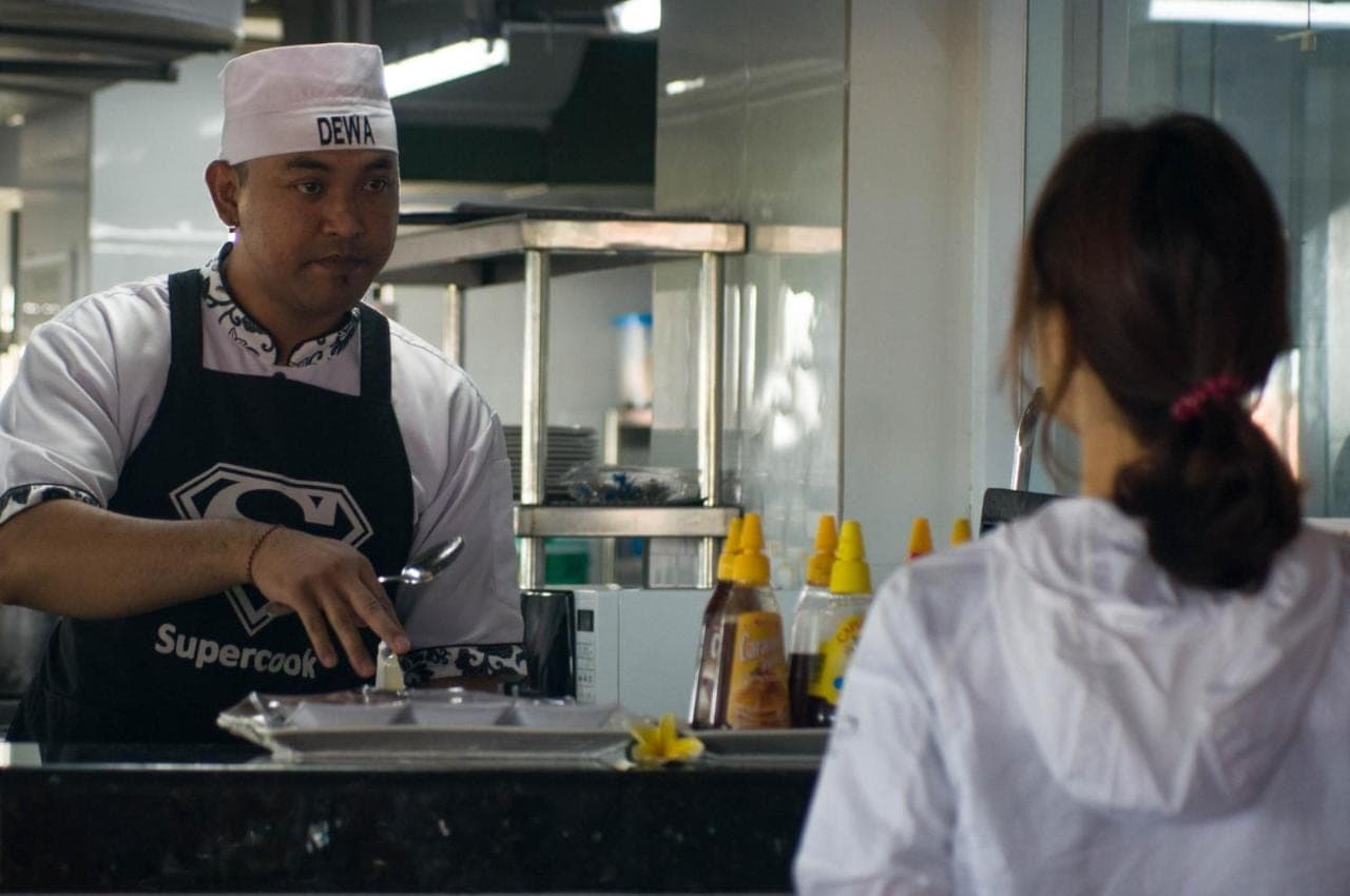 a man and a woman in a kitchen preparing food at Sulis Beach Hotel &amp; Spa in Kuta