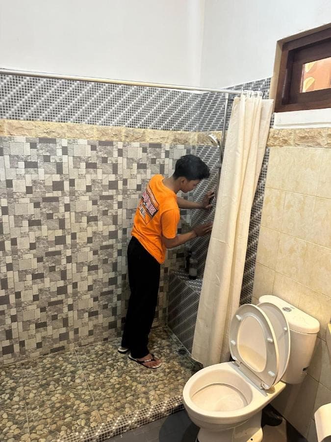 a woman standing in a bathroom next to a toilet at Jepun BnB Bali in Seminyak