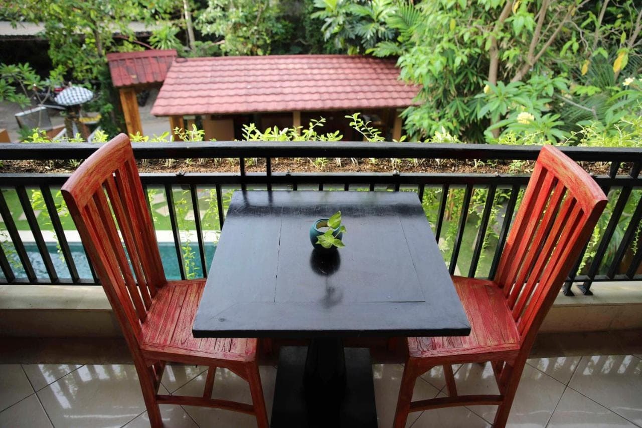 a wooden table with two chairs on a balcony at Jepun BnB Bali in Seminyak