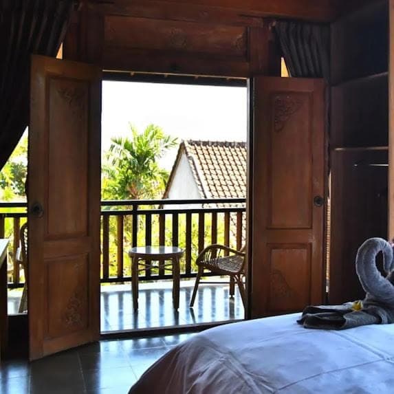 a bedroom with a bed and a view of a balcony at Putra'Lebah Amed Guest House in Amed