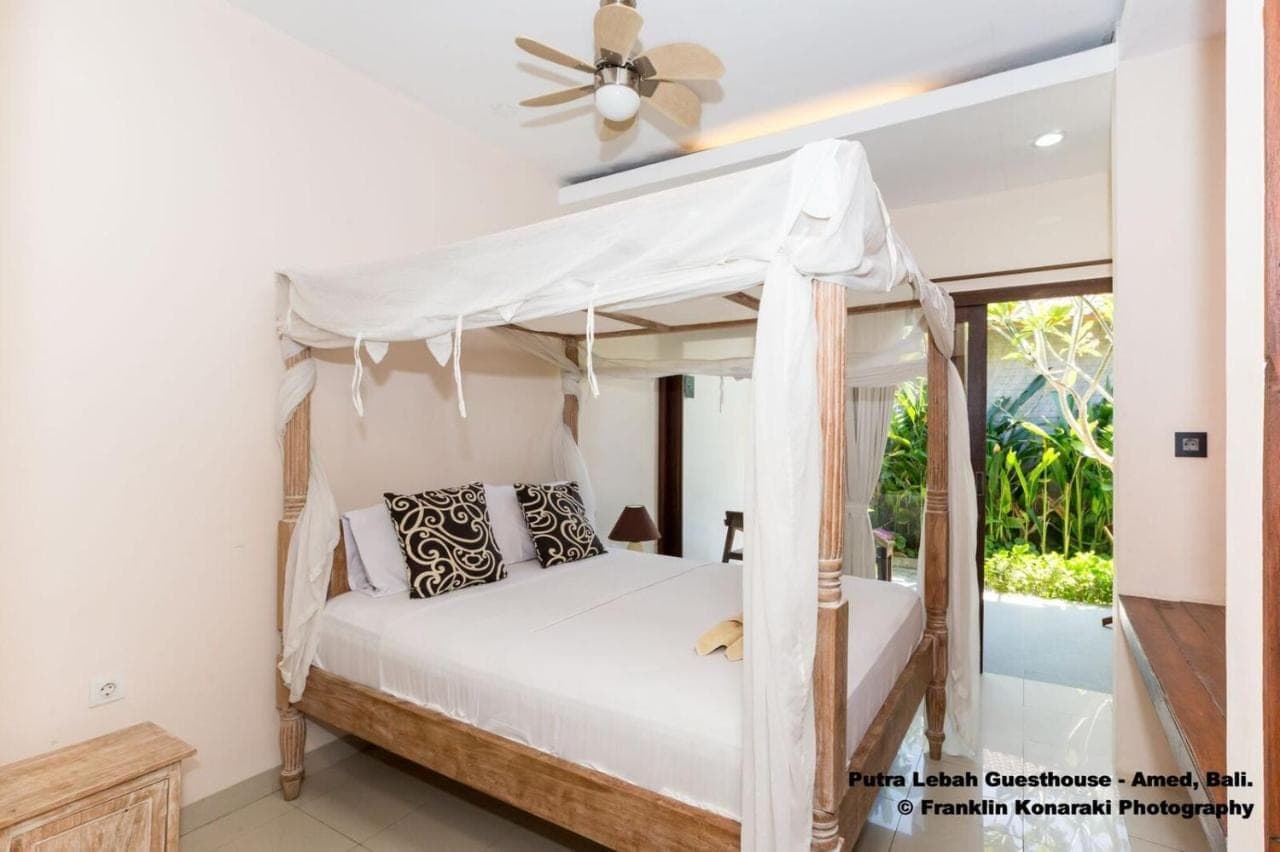 a bedroom with a bed and a ceiling fan at Putra'Lebah Amed Guest House in Amed