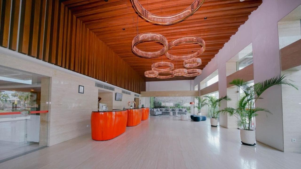 an office lobby with orange chairs and a wooden ceiling at Kuta Galleria Hotel in Kuta