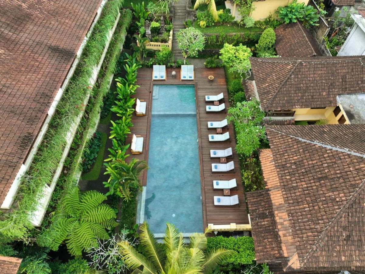 an overhead view of a swimming pool with chaise lounge chairs at Jati Cottage in Ubud