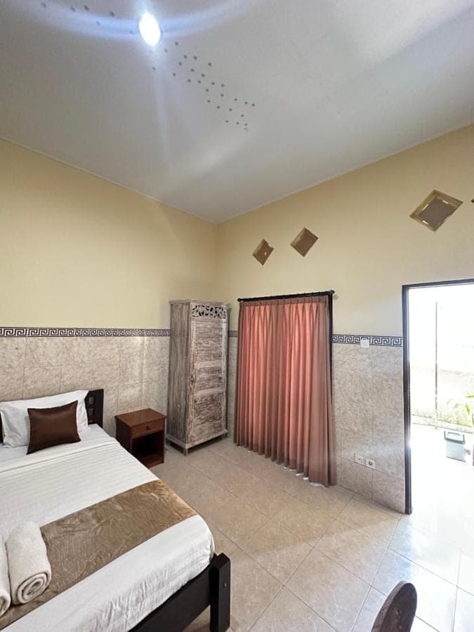a bedroom with a bed and a large window at OSA Guest House in Seminyak