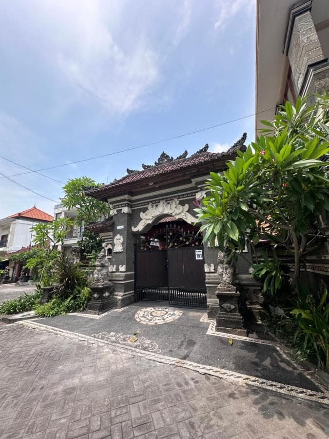a gate to a building with trees and a building at OSA Guest House in Seminyak