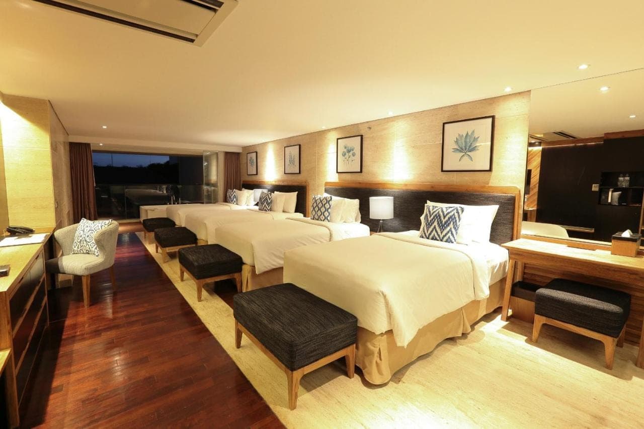 a hotel room with four beds and a desk at de Vins Sky Hotel Seminyak in Seminyak