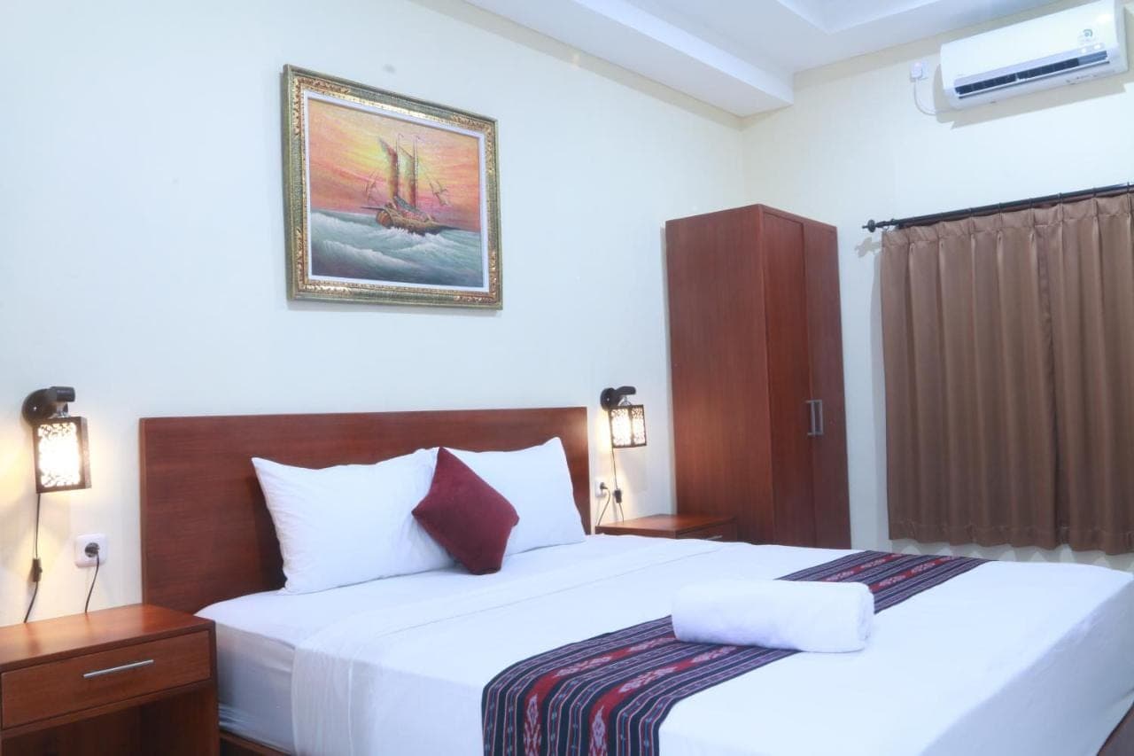 a hotel room with two beds and a picture on the wall at Sekar Waru Homestay in Sanur